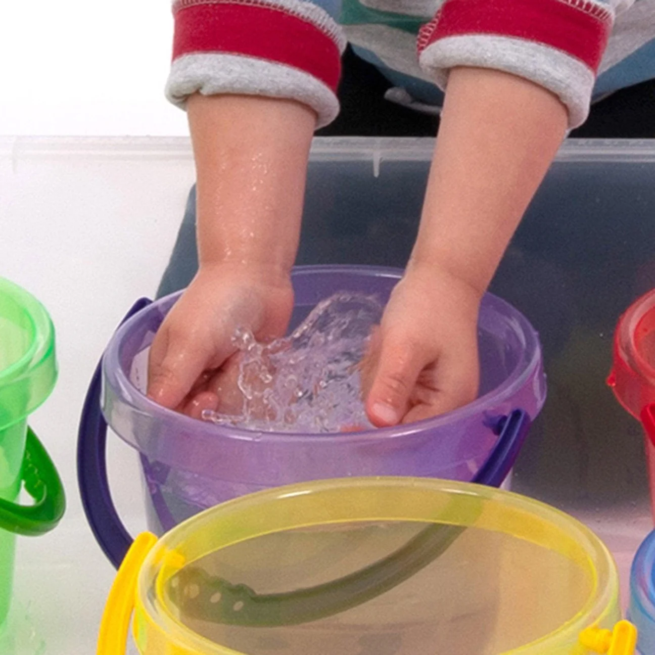 Cubos Tickit – Juego con agua Manos jugando con agua en un cubo translúcido morado Tickit